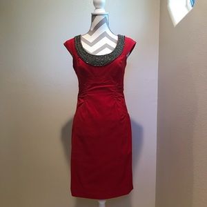 Red gathered dress with beaded neck line .